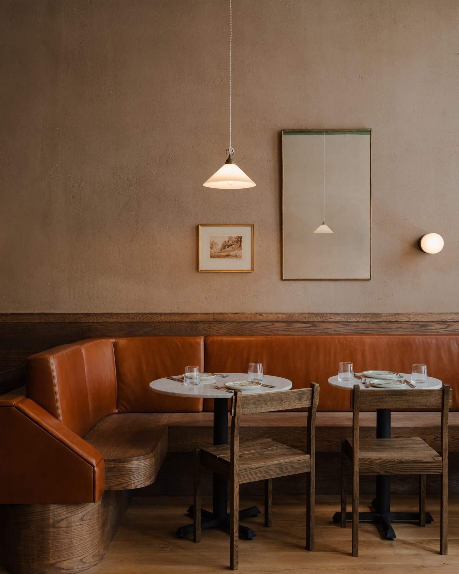 Smooth brown clay plaster above a terracotta leather banquette at Massara restaurant, New York.