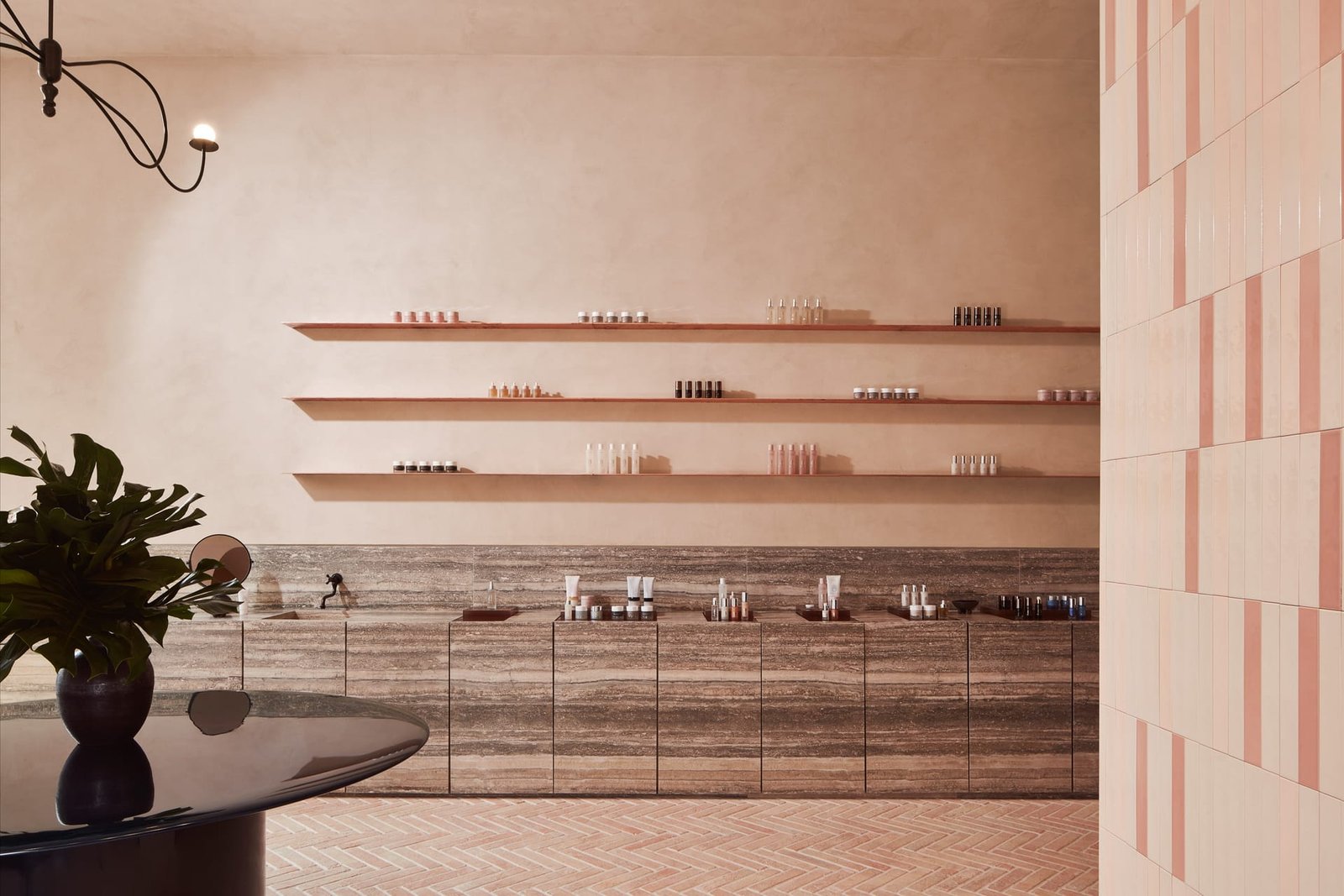 Retail room at Omorovicza Mayfair: three floating shelves of product on smooth white clay plaster above a travertine counter.