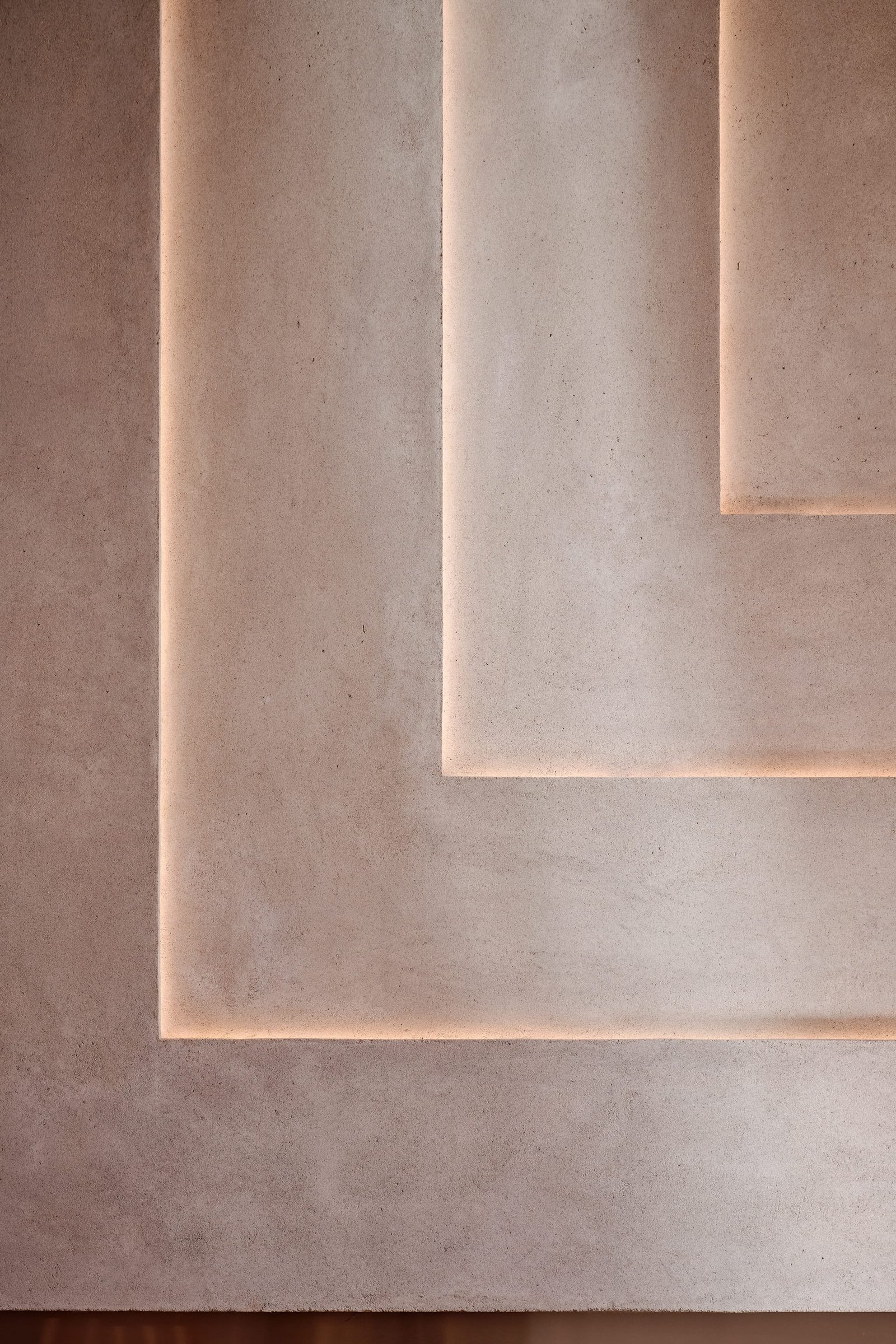 Detail of stepped relief panels in Demi Rustic clay plaster at Toplum, lit along their edges.