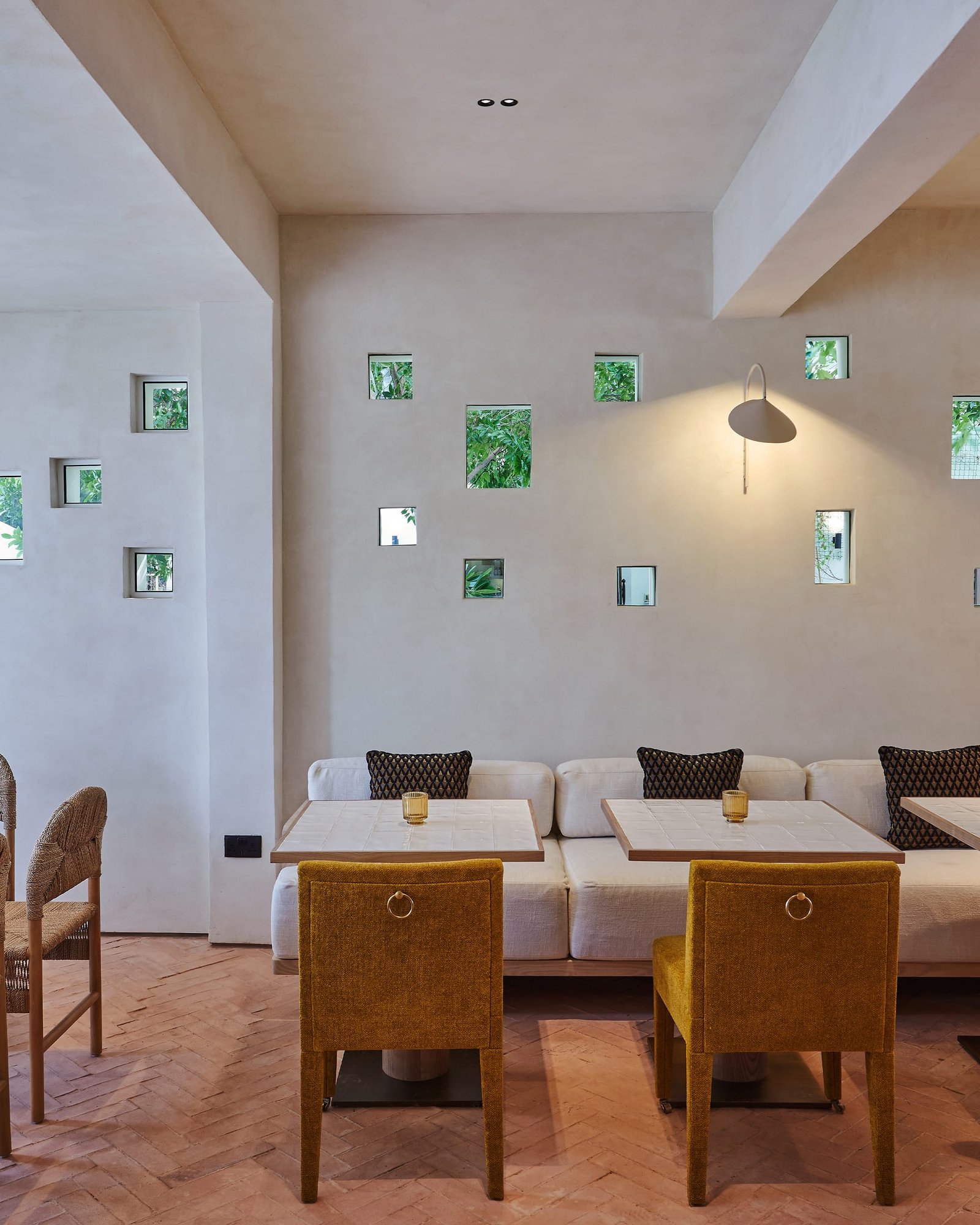 Villa 515 dining room in smooth white clay plaster with small square windows onto planting above a banquette.