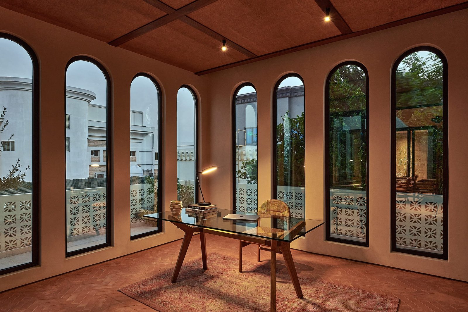 Perfumery room at Villa 515 with arched windows, a glass desk and clay-plastered walls and coffered ceiling.