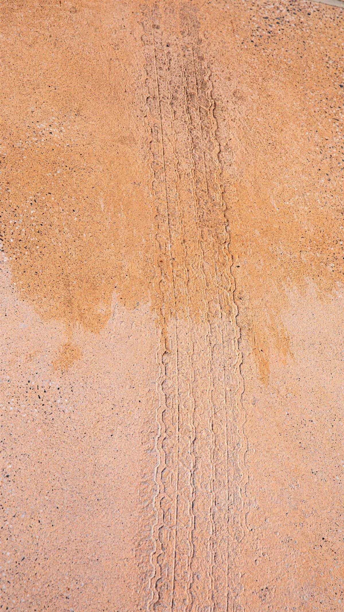 Overhead detail of salmon-pink exposed aggregate deck with dark and white chippings and an imprinted vehicle-track motif