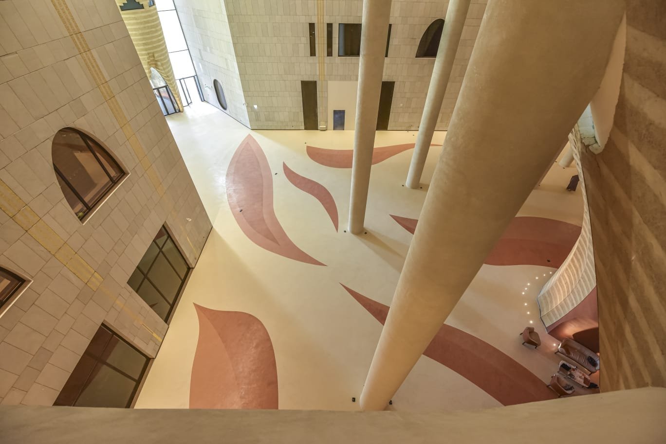 King Fahad Cultural Centre atrium, Riyadh: rose leaf inlays across the cream microcement floor between tapered columns.