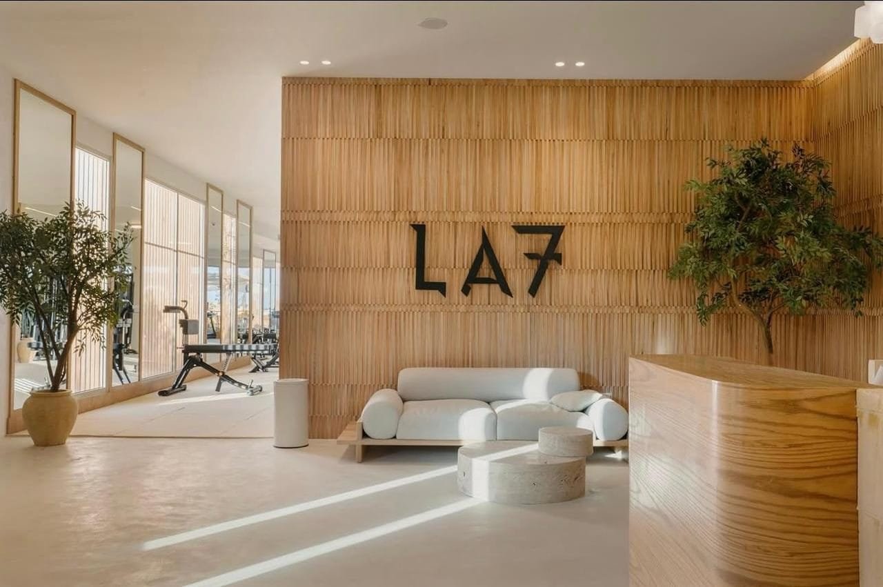 Sand-toned microcement reception wall meeting a slatted timber screen at LA7 Wellness Beach Club, Egypt