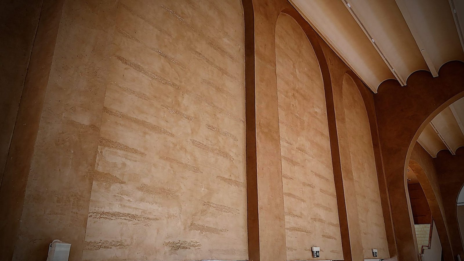 Banded decorative plaster gallery wall reading as horizontal strata at the Calligraphy Museum, Madinah