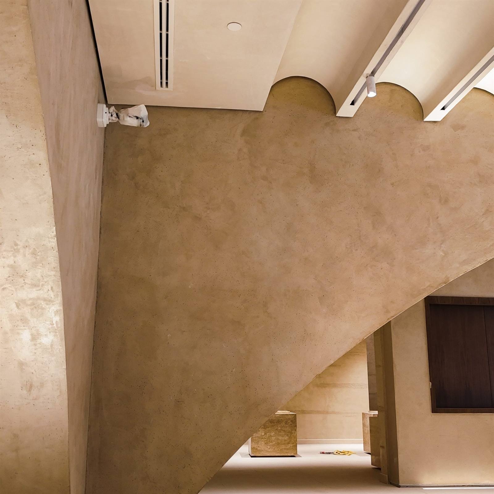 Underside of a stair in sand Microtadelakt lime plaster with a lit handrail at the Calligraphy Museum, Madinah