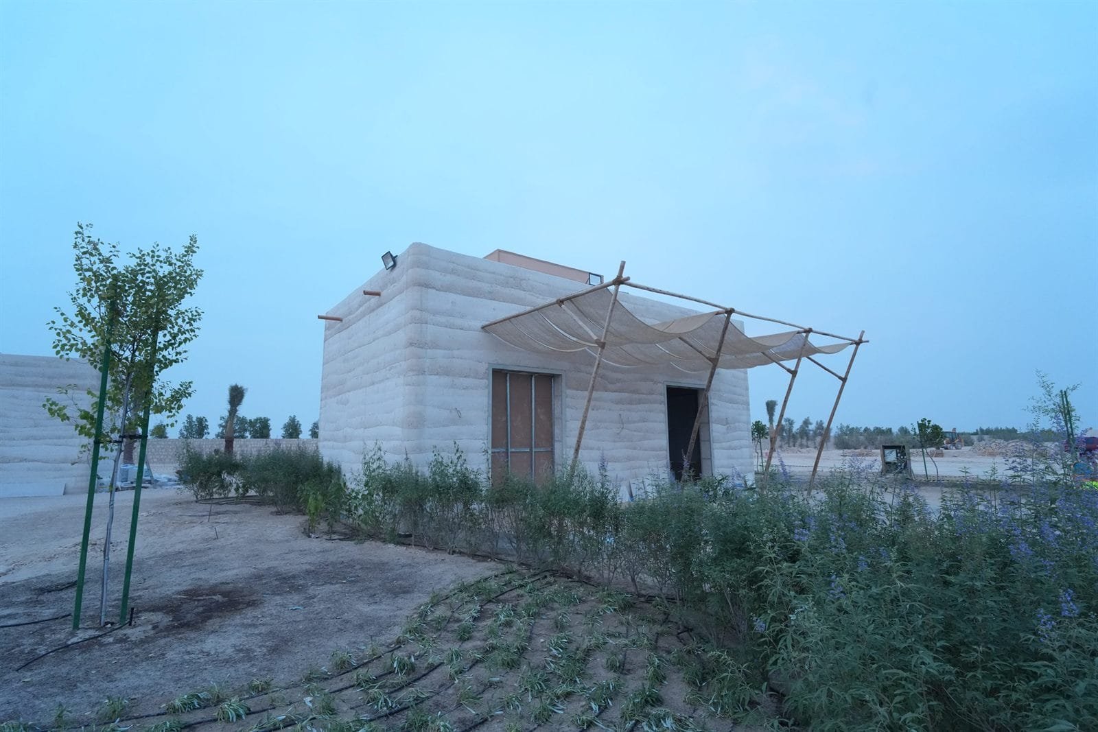 Completed in-situ rammed earth guest building with layered strata walls, Al Kaaban Resort