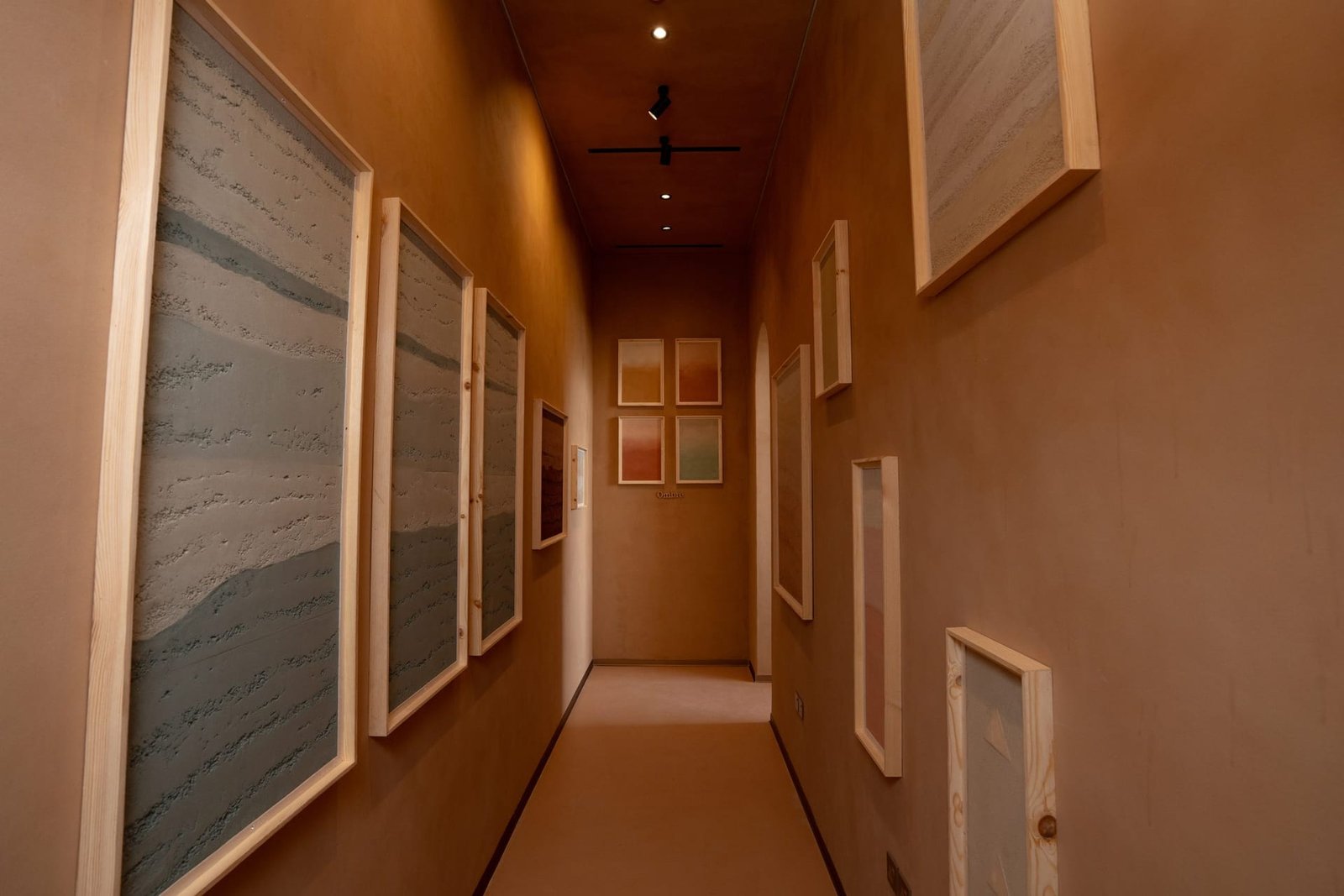 Rammed earth plaster sample corridor, framed strata panels on clay-plastered walls, Riyadh showroom