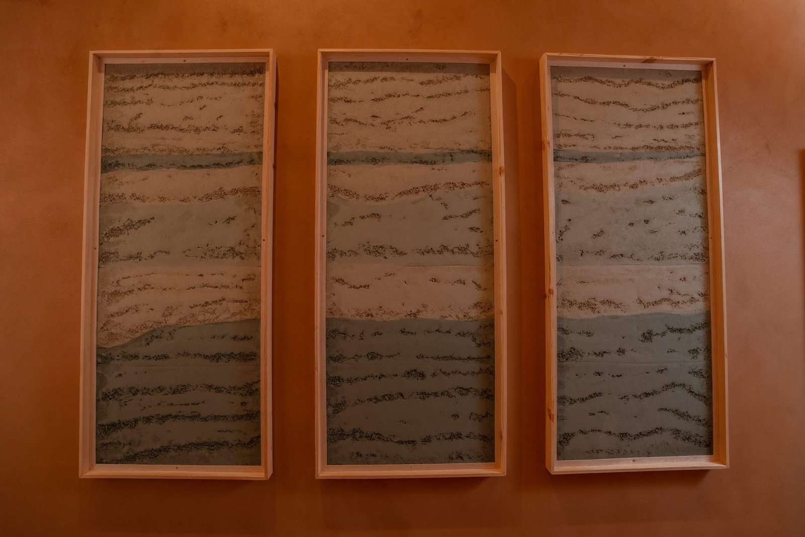 Three framed rammed earth plaster panels, cream and grey-green bands, Riyadh showroom